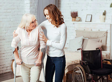 Young woman assists a senior woman with canes