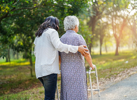 Middle aged woman assists elderly woman with a walker