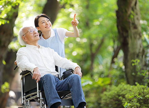 Young woman points something out to elderly man in wheelchair